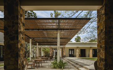 Wooden pergola with stone columns frames the pathway at Amansara, Cambodia.
