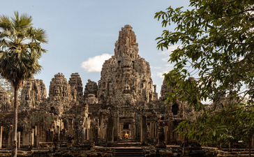 Stone towers of Bayon temple rise amongst tropical vegetation at Amansara's Angkor temple tour in Cambodia.