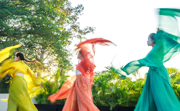 Colourful fabric dancers at Amansara beneath verdant foliage.