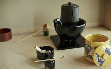 Matcha whisks and bowls arranged around a traditional stone mill at Aman Kyoto.