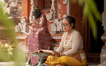 Woman practising Balinese numerology seated at Amandari's temple entrance, Ubud.