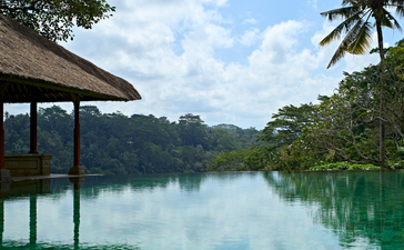 Amandari's swimming pool reflecting sky and tropical landscape, Indonesia.