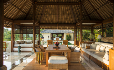 Amandari's open-sided pavilion with thatch roof, wooden furnishings, and garden views.