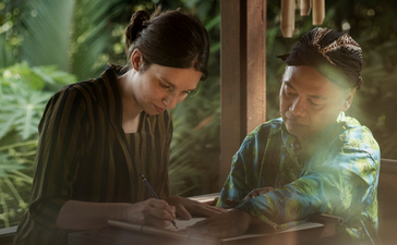 Two people sharing a quiet moment over tea at Amanjiwo resort, surrounded by lush greenery.