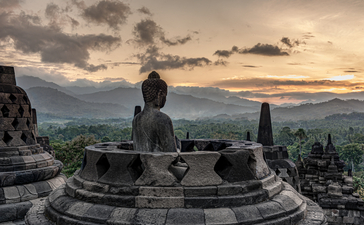 安缦齐和度假村佛教寺庙中的佛像雕像，背景为山谷和日落天空。
