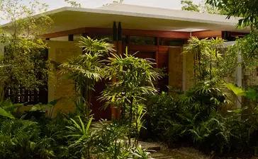 Exterior view of an accommodation pavilion at Amanera resort, surrounded by lush tropical greenery and a manicured lawn.