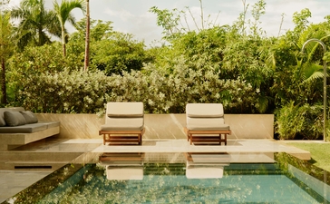 Amanera's landscape garden with striped wooden seating platform overlooking a reflecting pool and lush tropical foliage.