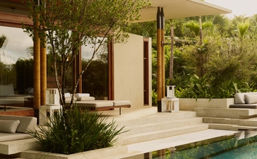 Amanera villa exterior with stone terrace, pool and lush tropical gardens at sunset.
