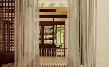 Couloir minimaliste avec colonnes blanches et détails bois à Amanera resort.