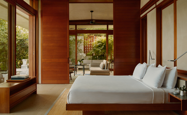 Hill Casita principal bedroom at Amanera with terracotta walls, wooden beams, and garden views through large windows.