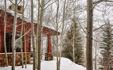 East Tatanka Home at Amangani set amongst snow-covered trees in winter, USA.