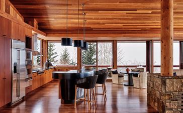 East Tatanka Home at Amangani: open-plan interior with wooden beams, dining area and views across the landscape.