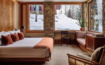 Principal bedroom at Amangani with wood-framed windows overlooking snowy landscape.
