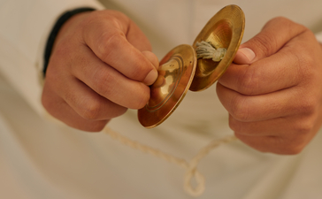 Hands holding brass cymbals during a yoga session at Amanbagh.