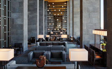 Aman Tokyo's lounge with seating arrangement facing an illuminated display wall and floor-to-ceiling windows.