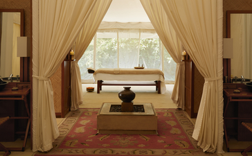 Spa treatment room at Aman-i-Khás with draped curtains, massage table, and natural light from windows.