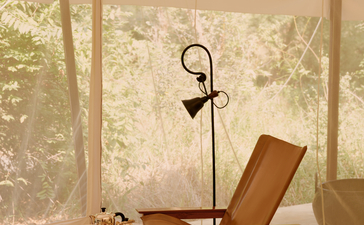 Tent interior at Aman-i-Khas with wooden furniture and canvas walls overlooking the landscape.