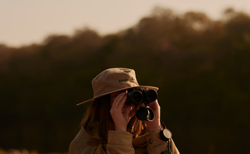 Safari guide at Aman-i-Khas observing wildlife through binoculars at dusk.