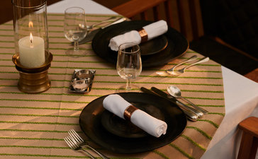 Private dining setup at Aman-i-Khas with candlelit table, place settings and wine in jungle setting.