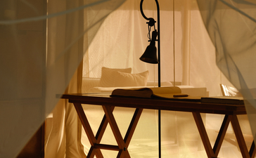 Candlelit workspace inside an Aman-i-Khas lounge tent, with a desk and chair beneath translucent fabric.