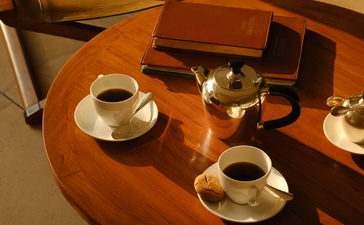 Wooden table in Aman-i-Khas lounge tent with coffee cups and leather accessories.