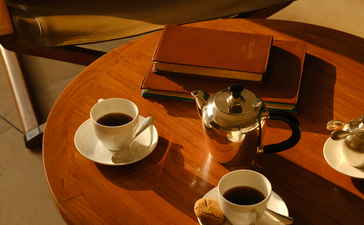 Overhead view of a wooden lounge tent table at Aman-i-Khas set with tea service and cushioned seating.