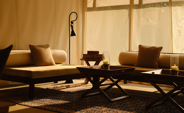 Aman-i-Khas lounge tent exterior with seating areas and warm golden lighting at dusk.