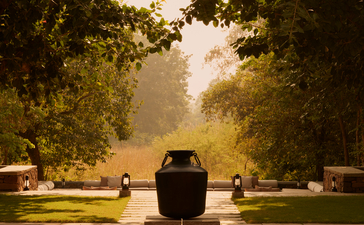 A central plunge pool at Aman-i-Khas framed by tree-lined pathways and dappled sunlight.