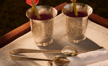 Welcome drinks served in gold vessels at Aman-i-Khas, garnished with red flowers and presented on marble.