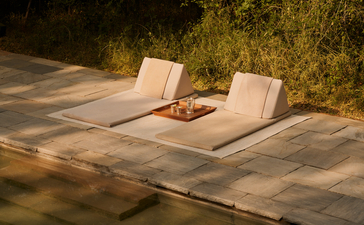 Two loungers on a stone deck beside a plunge pool at Aman-i-Khas, with illuminated greenery beyond.