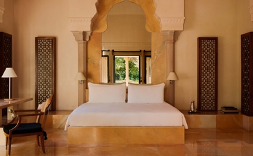Principal bedroom at Amanbagh with arched doorway and warm ochre walls.