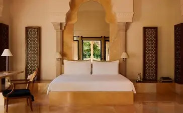 Principal bedroom at Amanbagh with arched doorway and warm ochre walls.