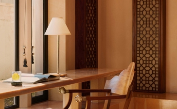Pool Pavilion dressing room at Amanbagh with carved wooden screens and mid-century chair.