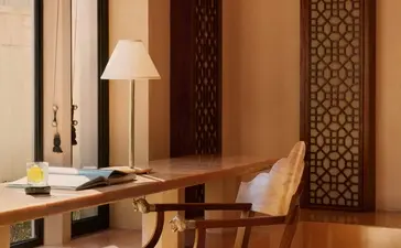 Pool Pavilion dressing room at Amanbagh with carved wooden screens and mid-century chair.
