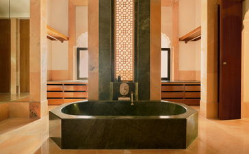 Courtyard Haveli Suite bathroom at Amanbagh with circular green stone soaking tub and twin mirrors.