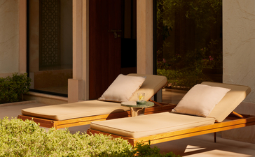 Wooden daybed with cream cushions in the courtyard at Amanbagh, India.