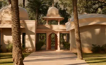 Pool pavilion exterior at Amanbagh, India, with arched doorways and palm trees.