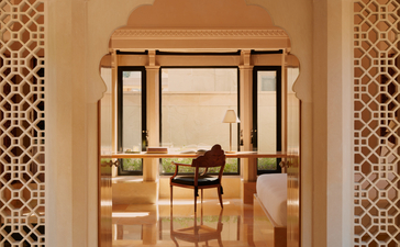 Pavilion desk overlooking the pool at Amanbagh, framed by carved stone archway.