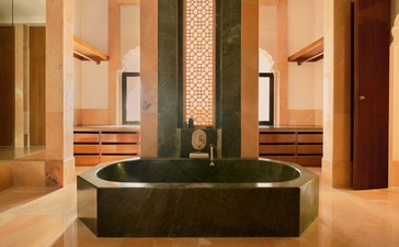 Courtyard haveli suite with symmetrical archways, central soaking tub, and warm stone walls at Amanbagh.