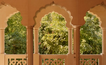 Garden view through arched stone windows at Amanbagh, India.