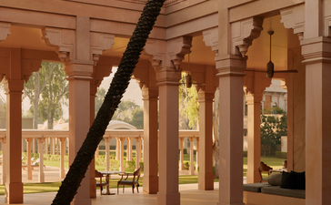 Amanbagh's main building exterior showing carved wooden screens and columns framing views of the courtyard gardens.