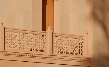 Amanbagh's main building exterior detail showing carved stone balcony with decorative lattice work and traditional architectural elements.