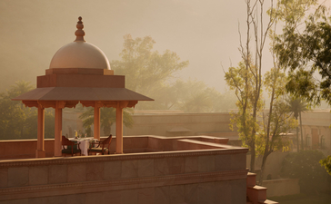 Amanbagh's main building exterior with a domed pavilion emerging from morning mist in Rajasthan.