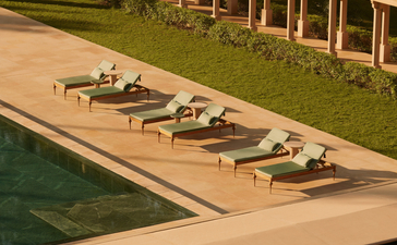 Sunbeds arranged along the poolside at Amanbagh, India, with covered pavilions beyond.