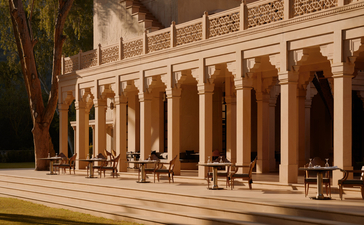 Restaurant terrace at Amanbagh with arched colonnade and warm stone architecture at dusk.