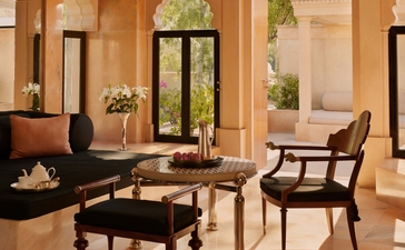 Terrace Haveli Suite lounge at Amanbagh, with sandstone archways, dark wooden seating and views to the courtyard.