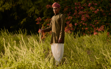 Gardener at Amanbagh standing in grounds with flowering plants in background.