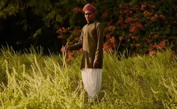 Gardener at Amanbagh standing in grounds with flowering plants in background.