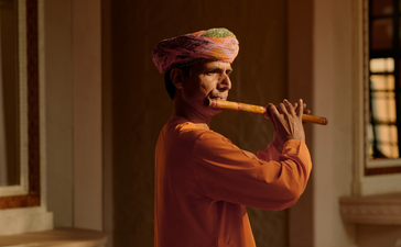 Musician performing at Amanbagh, India, playing a traditional stringed instrument indoors.
