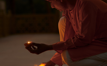 Artisan creating a traditional rangoli pattern by candlelight at Amanbagh.